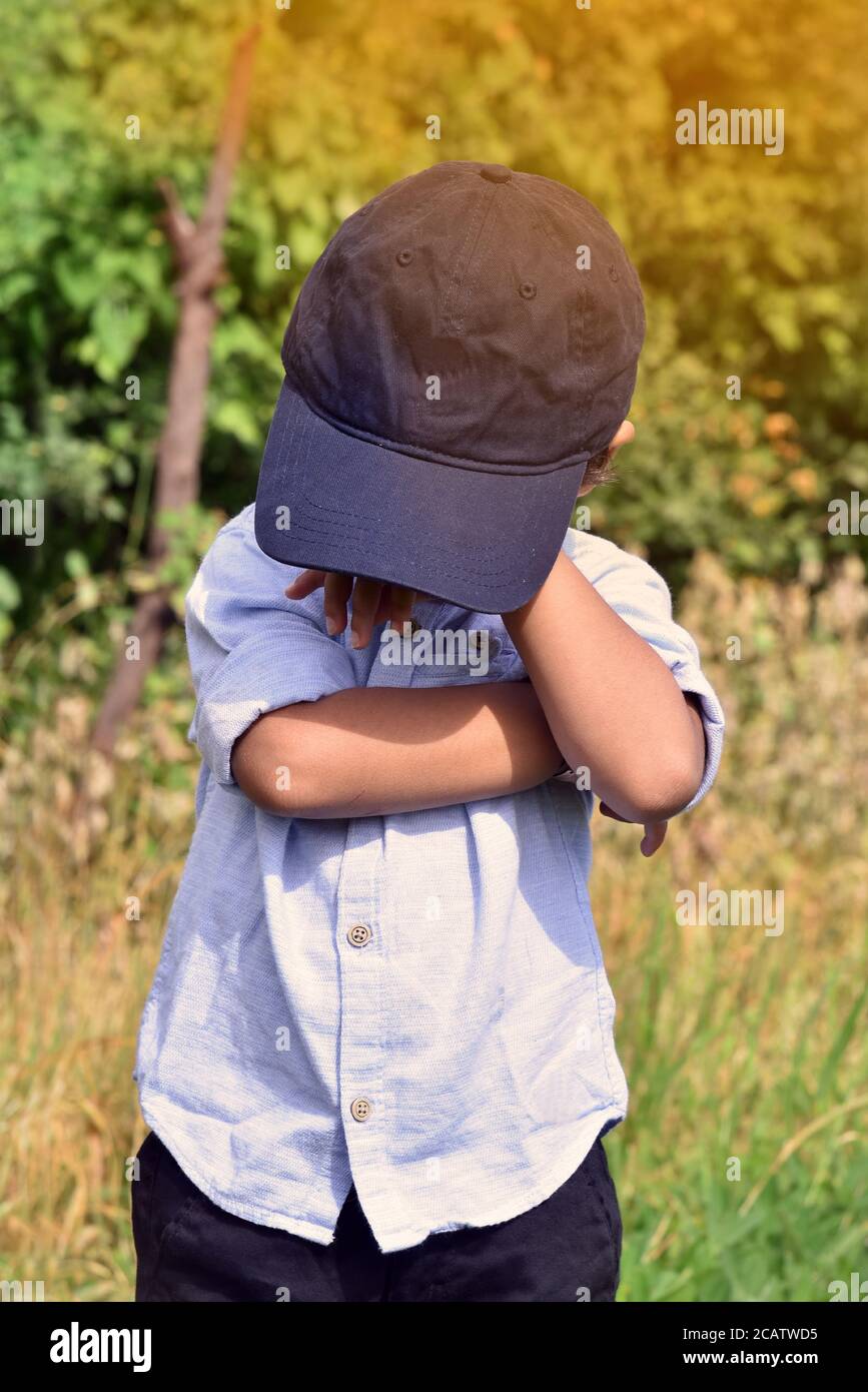 Trauriger weinender kleiner Junge bedeckt sein Gesicht mit Händen Outdoor Stock Bild. Stockfoto