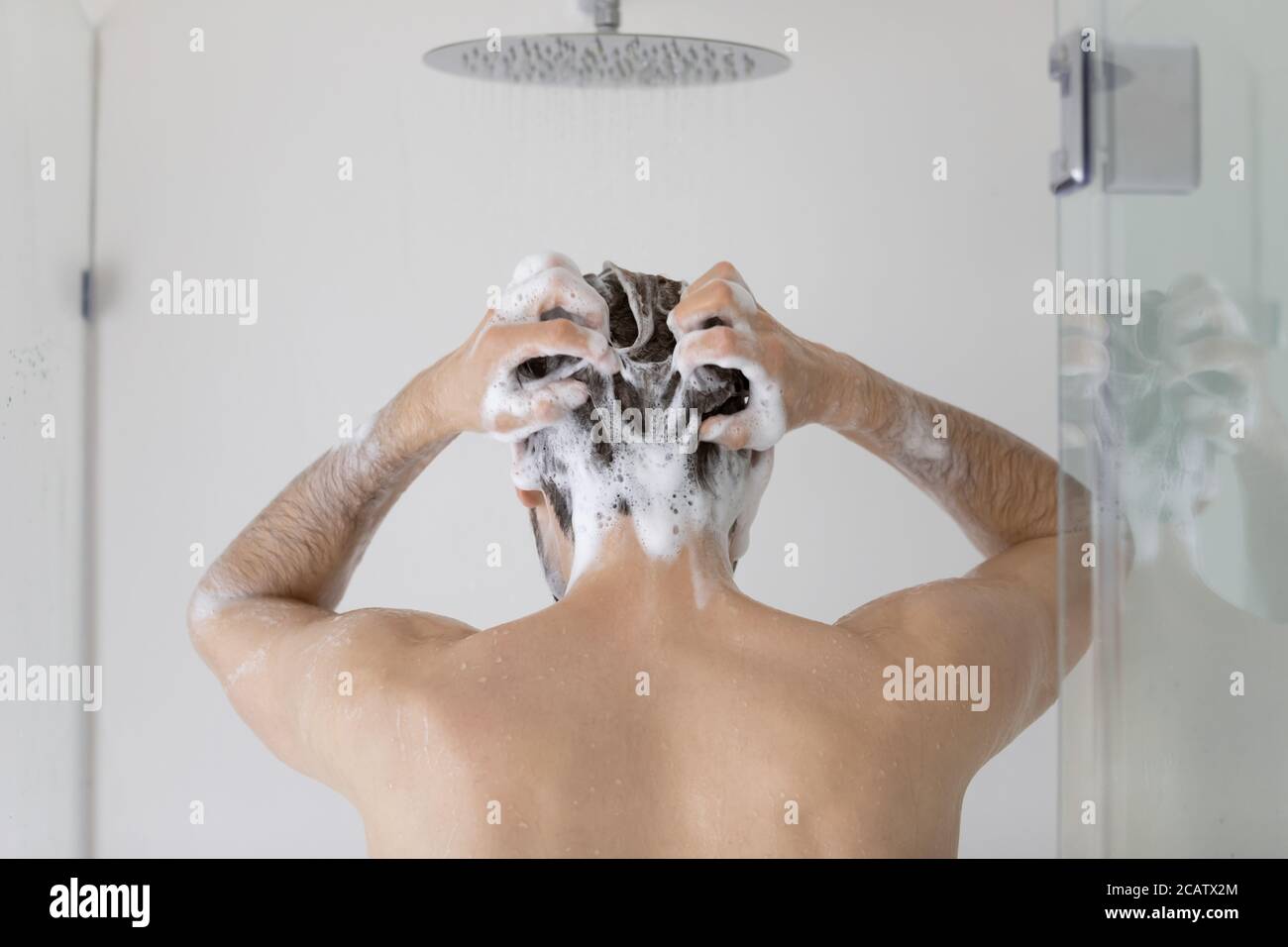 Rückansicht junger Mann Haare waschen, im Badezimmer stehen Stockfoto