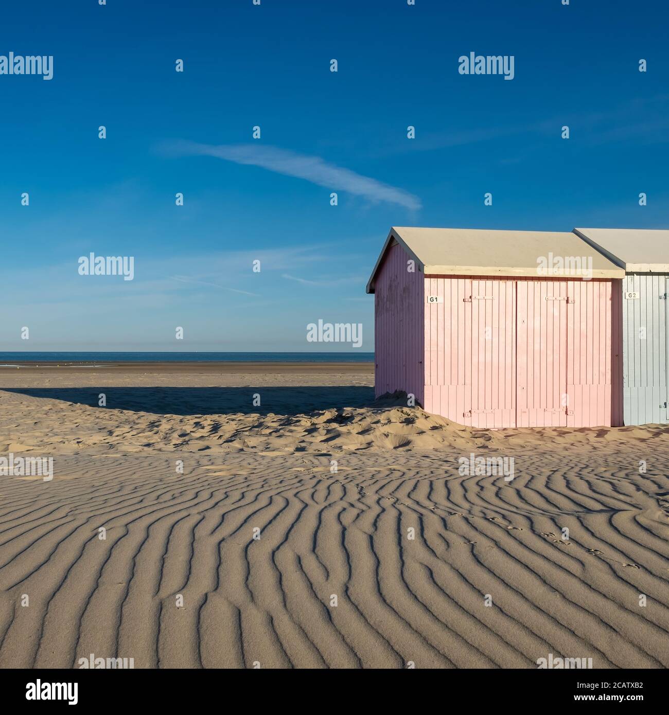 Sandmuster führen zu pastellfarbenen Strandhütten Stockfoto