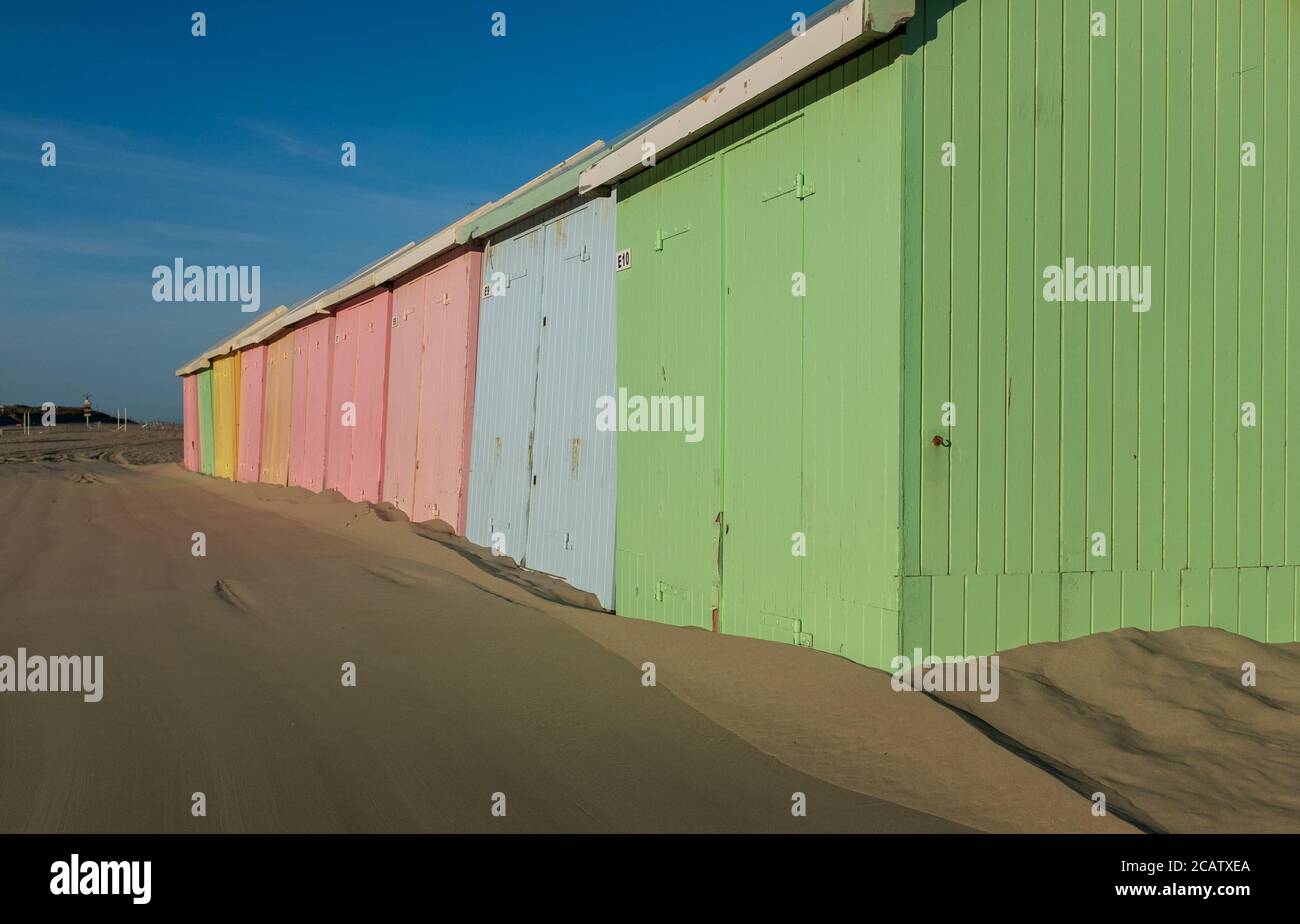 Pastellfarbene Strandhütten Reihen sich am einsamen Strand von Berck in Frankreich aneinander. Stockfoto