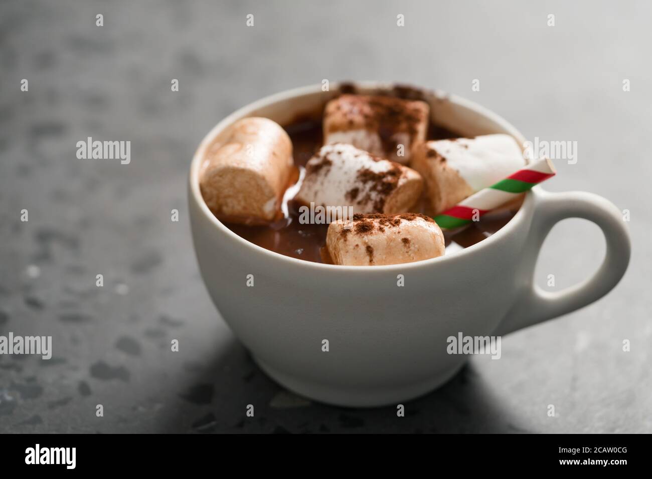 Kakao-Getränk mit Marshmallow und weihnachtliches Trinkhalm in weiß tasse auf Terrazzo-Oberfläche mit Kopierraum Stockfoto