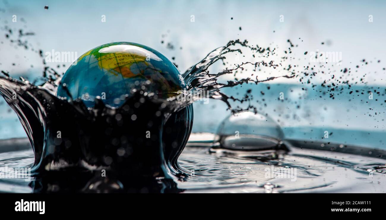 Die Erde in Form eines Erdballs fällt in das Öl und spritzt. Konzept der Umweltverschmutzung, Nutzung der natürlichen Ressourcen und Schaden für die Umwelt Stockfoto