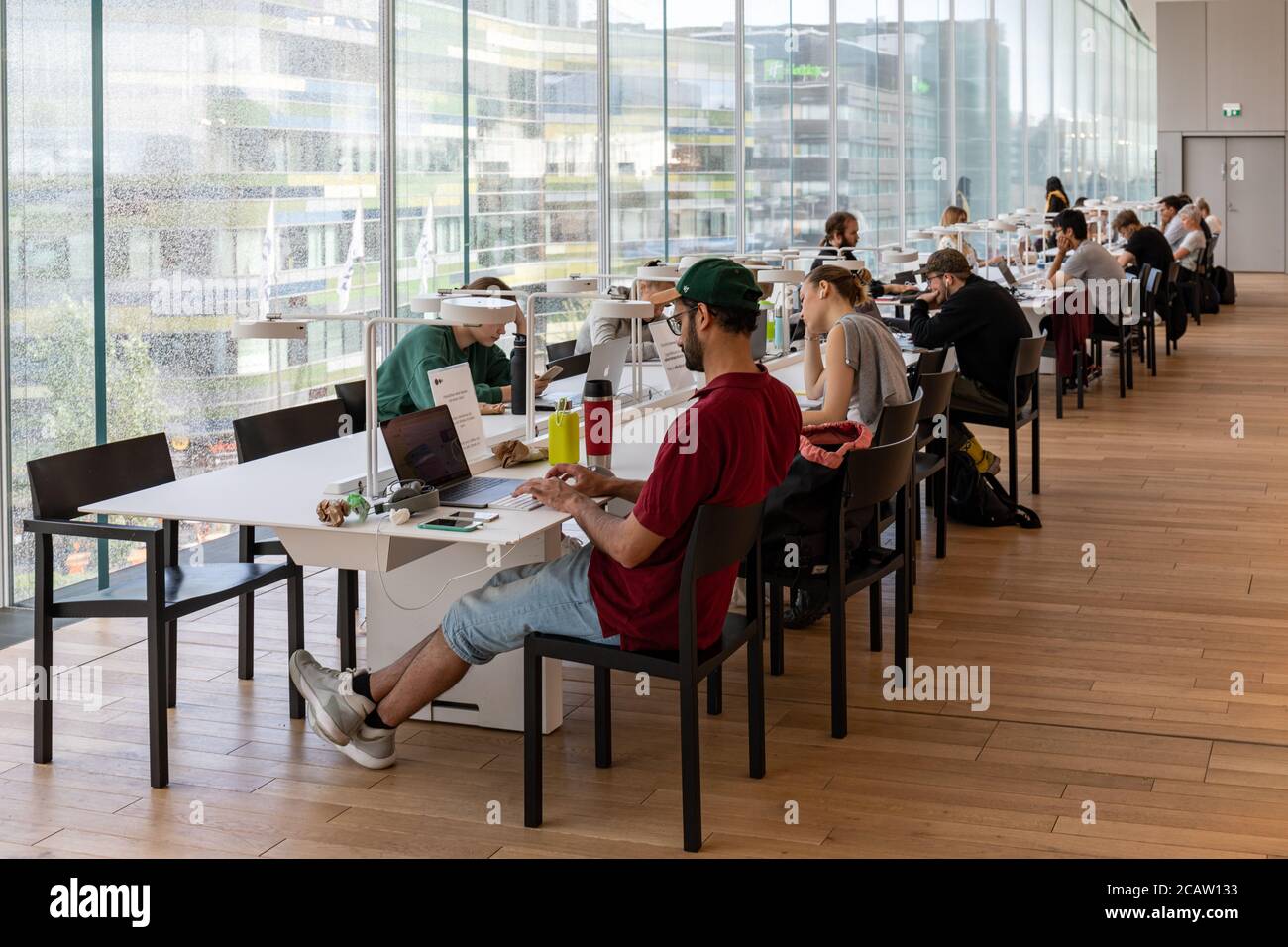 Personen, die an einem der Oodi-Arbeitsstationen der Zentralbibliothek in Helsinki, Finnland, mit Laptops arbeiten Stockfoto