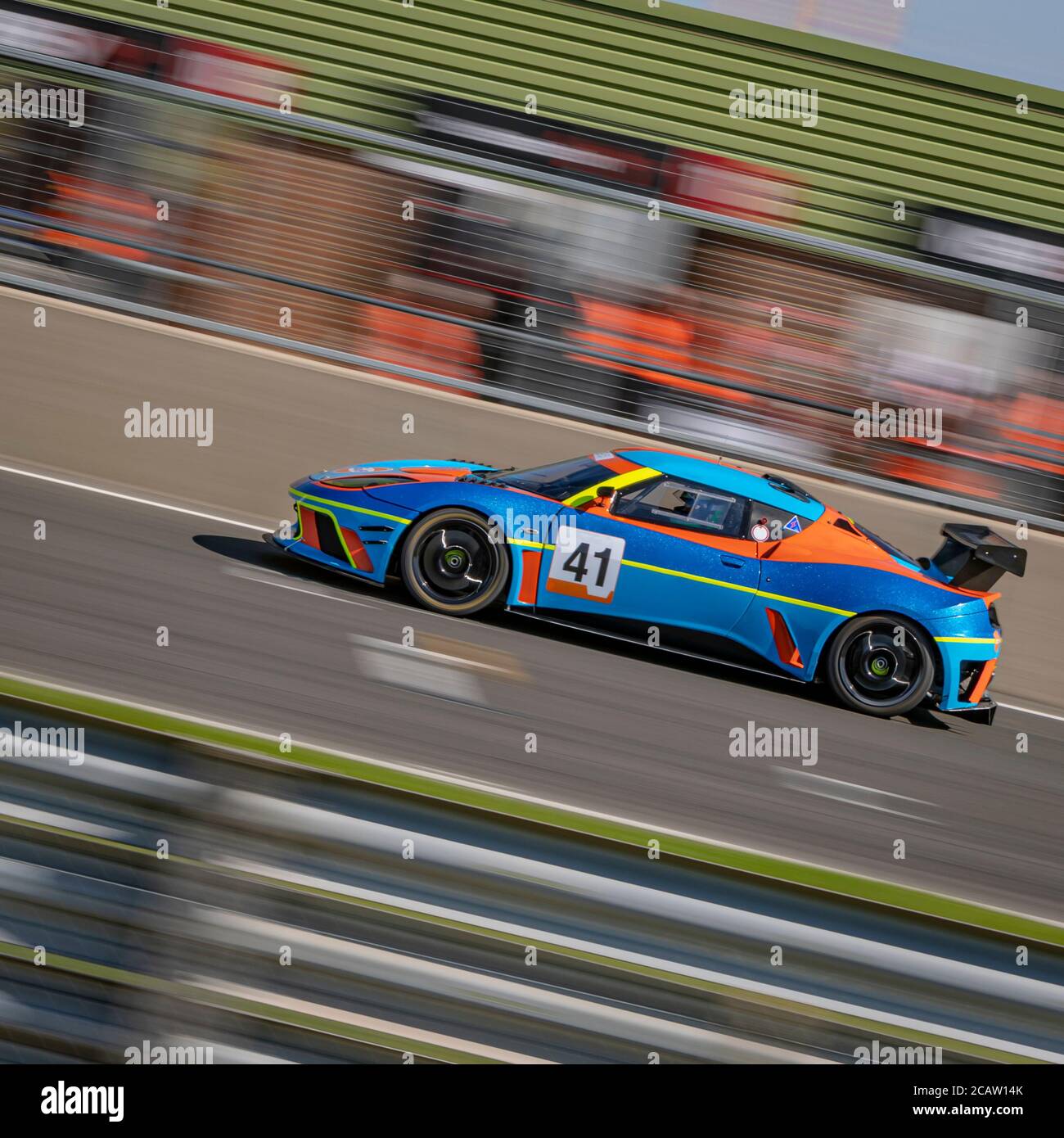 Eine Schwenkaufnahme eines blauen und orangenen Rennwagens, der eine Strecke fährt. Stockfoto