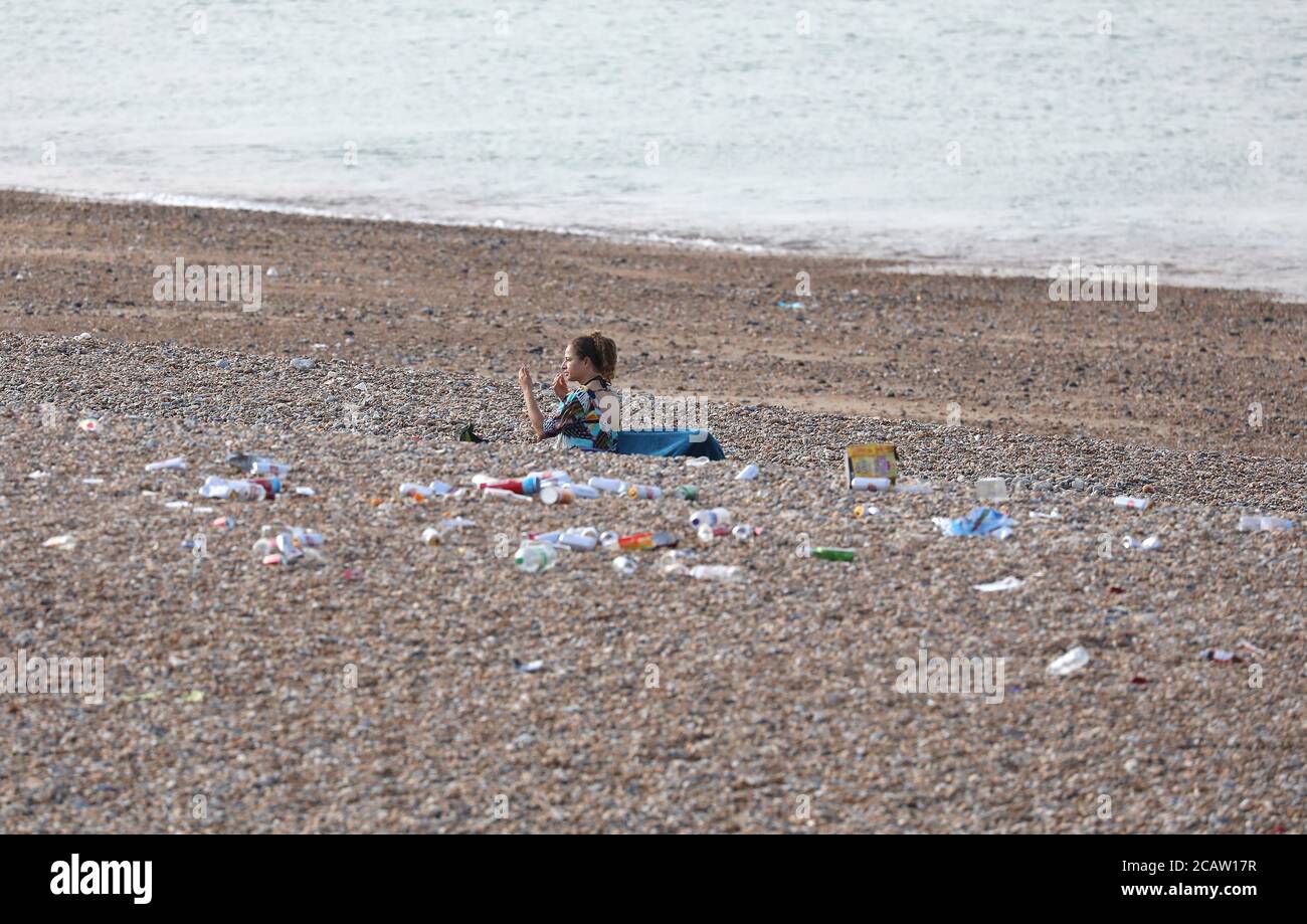Brighton, Großbritannien. August 2020. Eine Frau sitzt im Müll am Brighton Beach nach einem anstrengenden Tag im Resort gestern. Kredit: James Boardman/Alamy Live Nachrichten Stockfoto