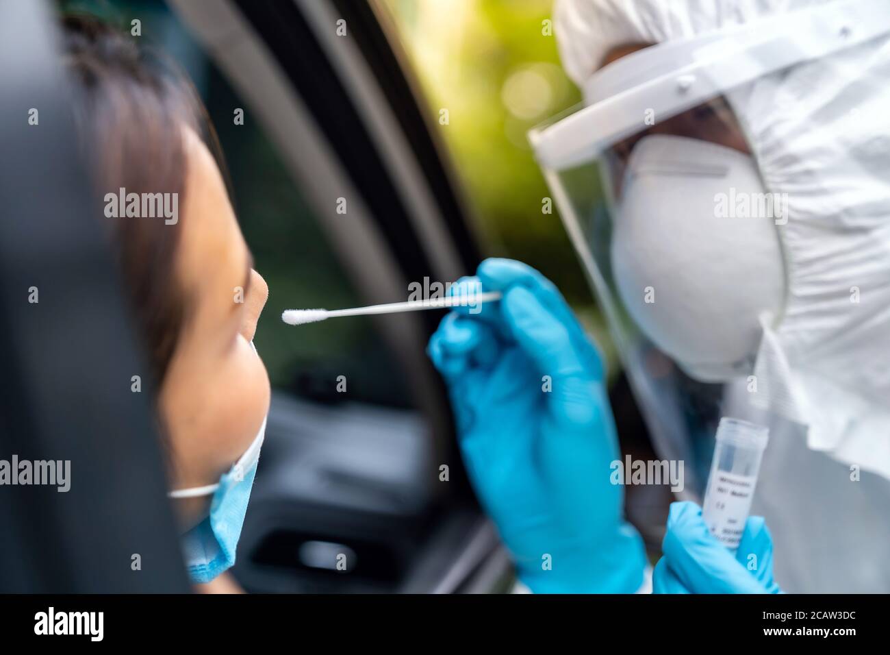 Portrait der asiatischen Frau Drive thru Coronavirus covid-19 Test durch medizinisches Personal mit PSA Anzug von Nase Tupfer. Neue normale Gesundheitsversorgung Drive-Thru-Service und Stockfoto