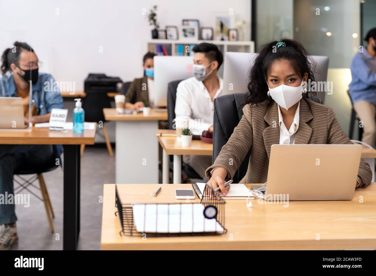 Portrait gemischte Rasse der afrikanischen schwarzen und asiatischen Büroangestellte tragen Gesichtsmaske arbeiten in neuen normalen Büro mit sozialen Abstand zu Gruppe von Business-Tee Stockfoto