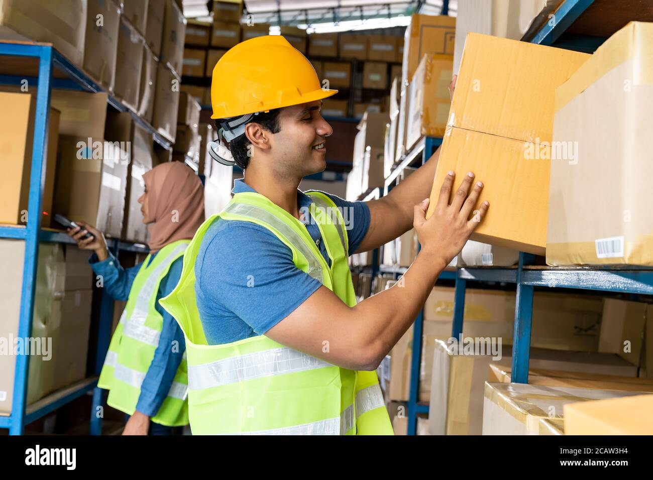 Indischer Lagerarbeiter legte Karton in das Regal mit muslimischer Islam asiatische Arbeiter Inventar in Lager Verteilungszentrum Umwelt zu tun. Verwenden Stockfoto