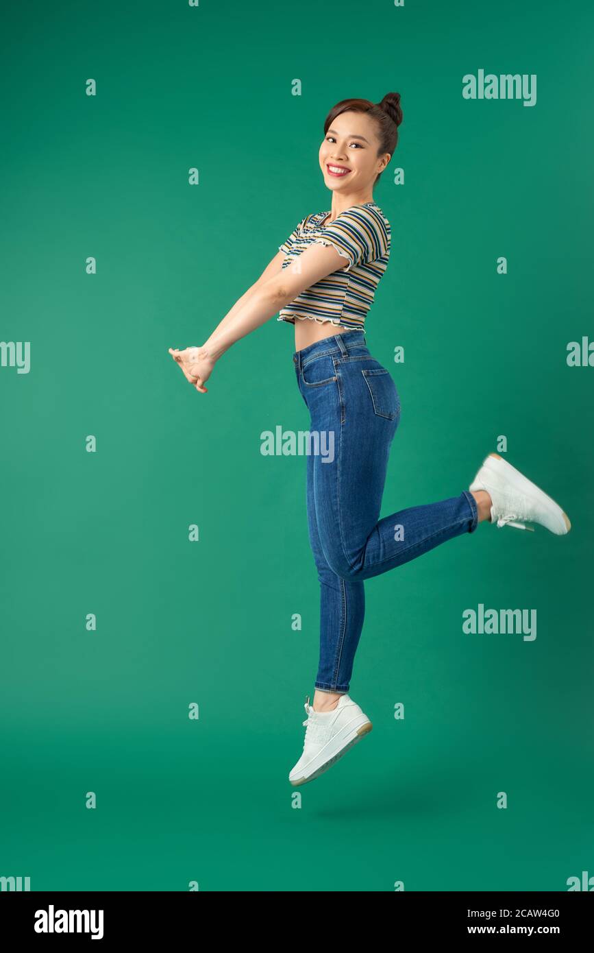 Volle Länge des Portraits der fröhlichen jungen asiatischen Frau springen in der Luft über grünen Hintergrund. Stockfoto