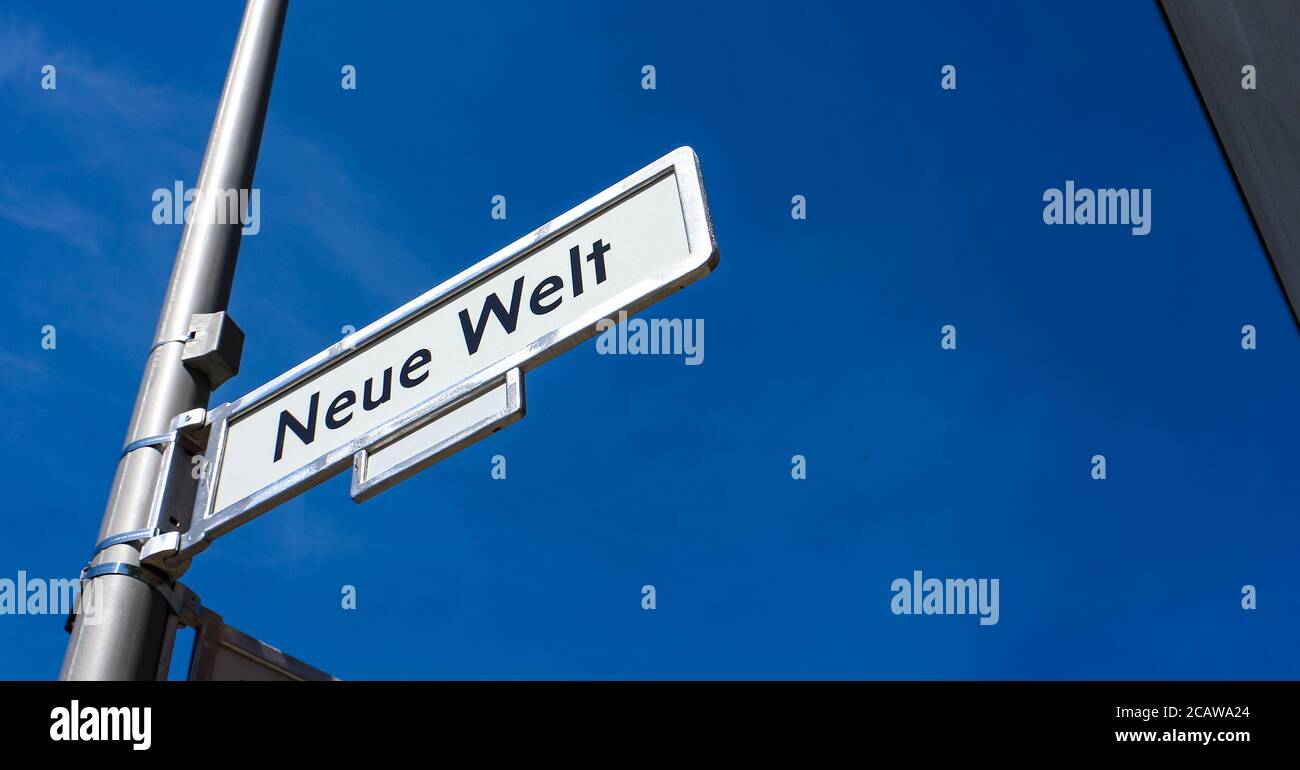 'Neue Welt' ungewöhnliches Straßennamen-Straßenschild vor blauem Himmel im Berliner Stadtteil Friedrichshain. Stockfoto