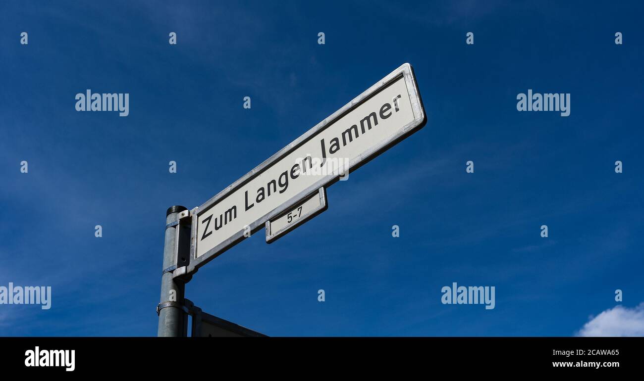 'Zum Langen Jammer' ungewöhnliches Straßennamen-Straßenschild vor blauem Himmel im Stadtteil Friedrichshain, Berlin, Deutschland. Stockfoto