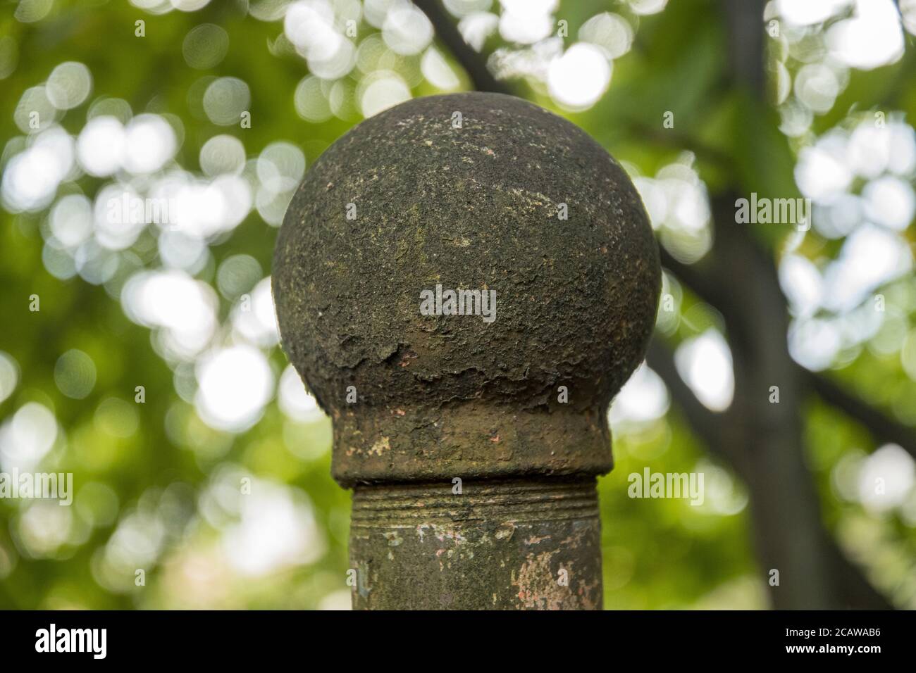 Nahaufnahme einer moosigen Steinrunde mit weißer Säule Bokeh leuchtet im Hintergrund Stockfoto