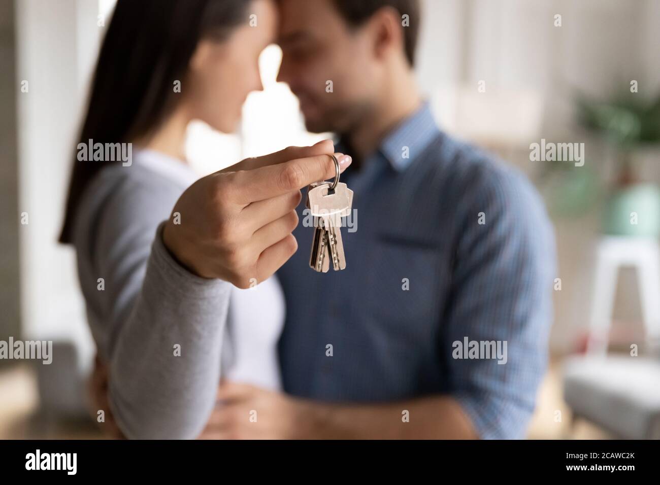 Emotionales glückliches Familienpaar, das Schlüssel aus dem neuen Haus vorführt. Stockfoto