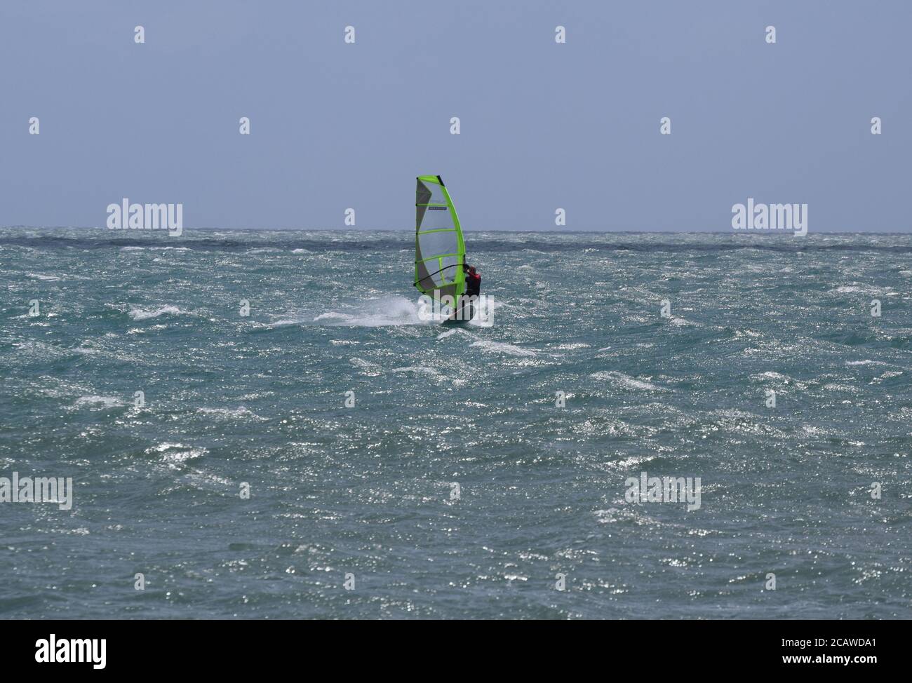 Windsurfer auf schimmerndem Meer Stockfoto