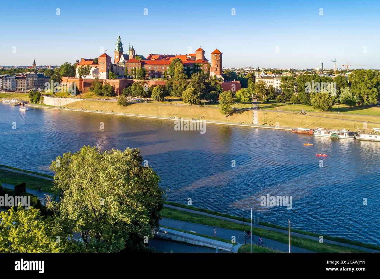 Königliche Wawel-Kathedrale und Schloss in Krakau, Polen. Luftaufnahme bei Sonnenuntergang. Weichsel, Touristenboote, Kanus, Flussufer mit Bäumen, Parks, p Stockfoto