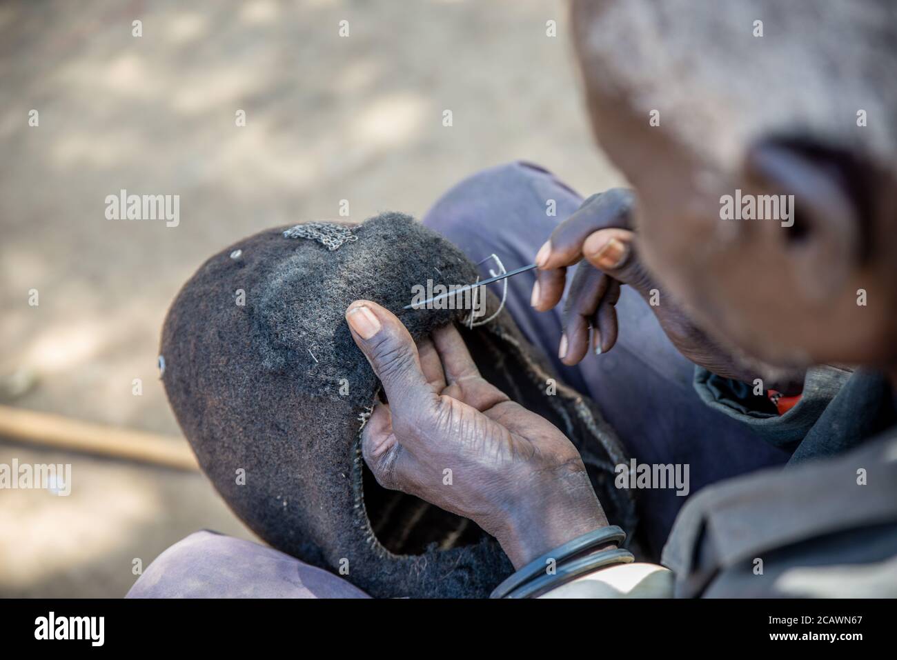 Alter Karamojong-Mann, der eine Etimat (epukot)-Hideaddress aus menschlichem Haar und Straußenfedern aufrechterhält, Moroto District, Uganda Stockfoto