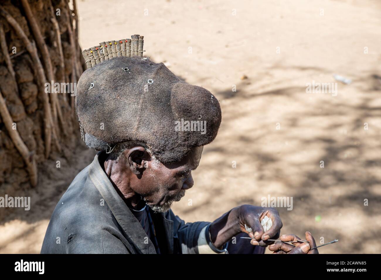 Alter Karamojong-Mann, der eine Etimat (epukot)-Hideaddress aus menschlichem Haar und Straußenfedern aufrechterhält, Moroto District, Uganda Stockfoto