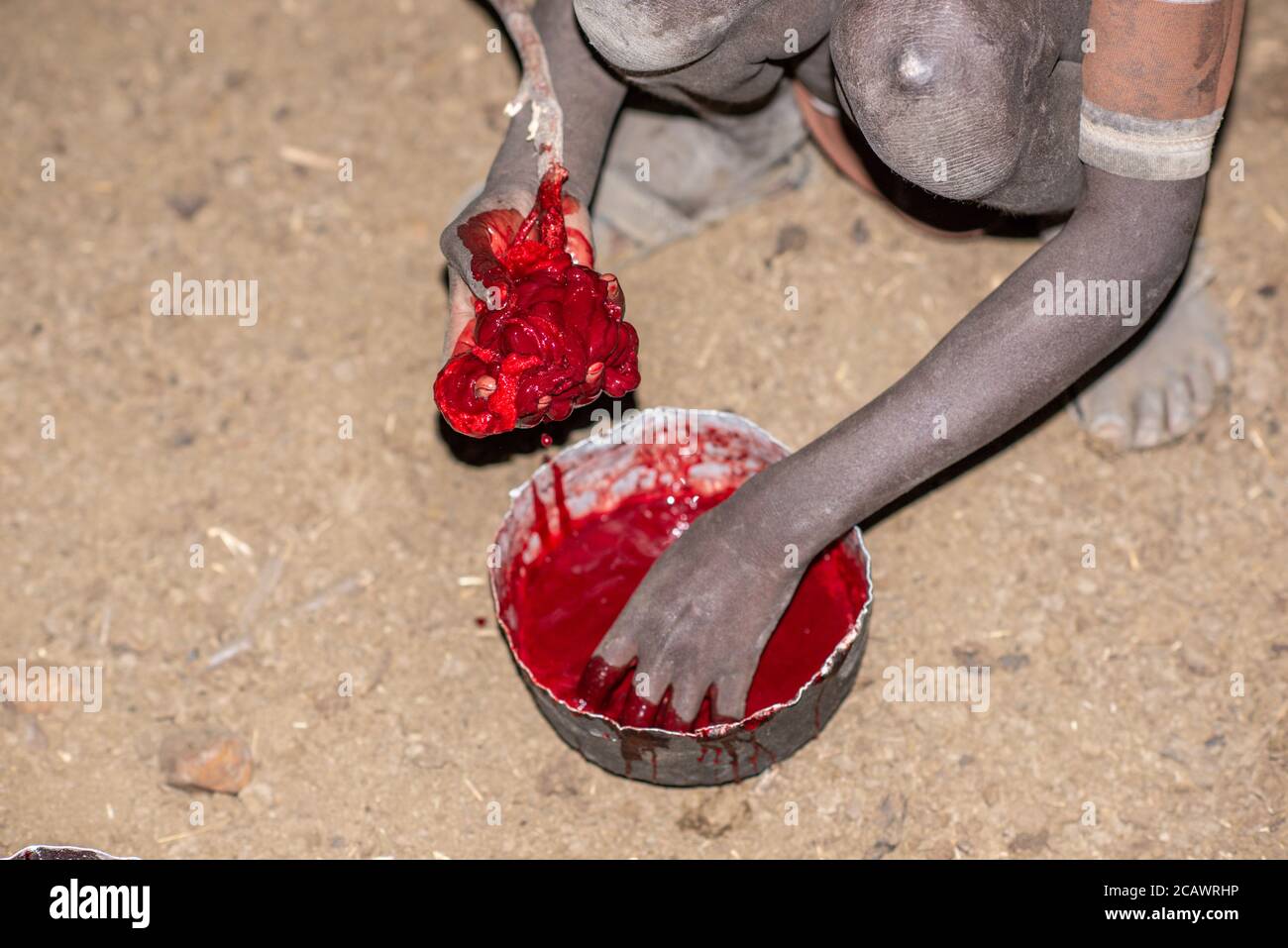 Reinigung von frischem Blut von Gerinnseln in einer Karamojong-Siedlung bei Nacht, Moroto District, Uganda Stockfoto