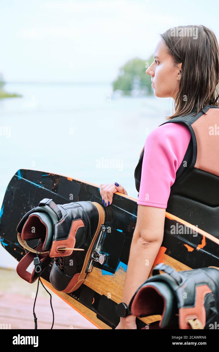 Junge Surferin mit Surfbrett, das am Wasser davor steht Der Kamera Stockfoto