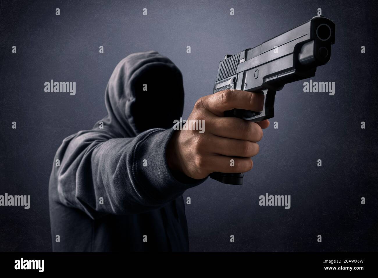 Mit Kapuze Mann mit einer Pistole in der Dunkelheit Stockfoto