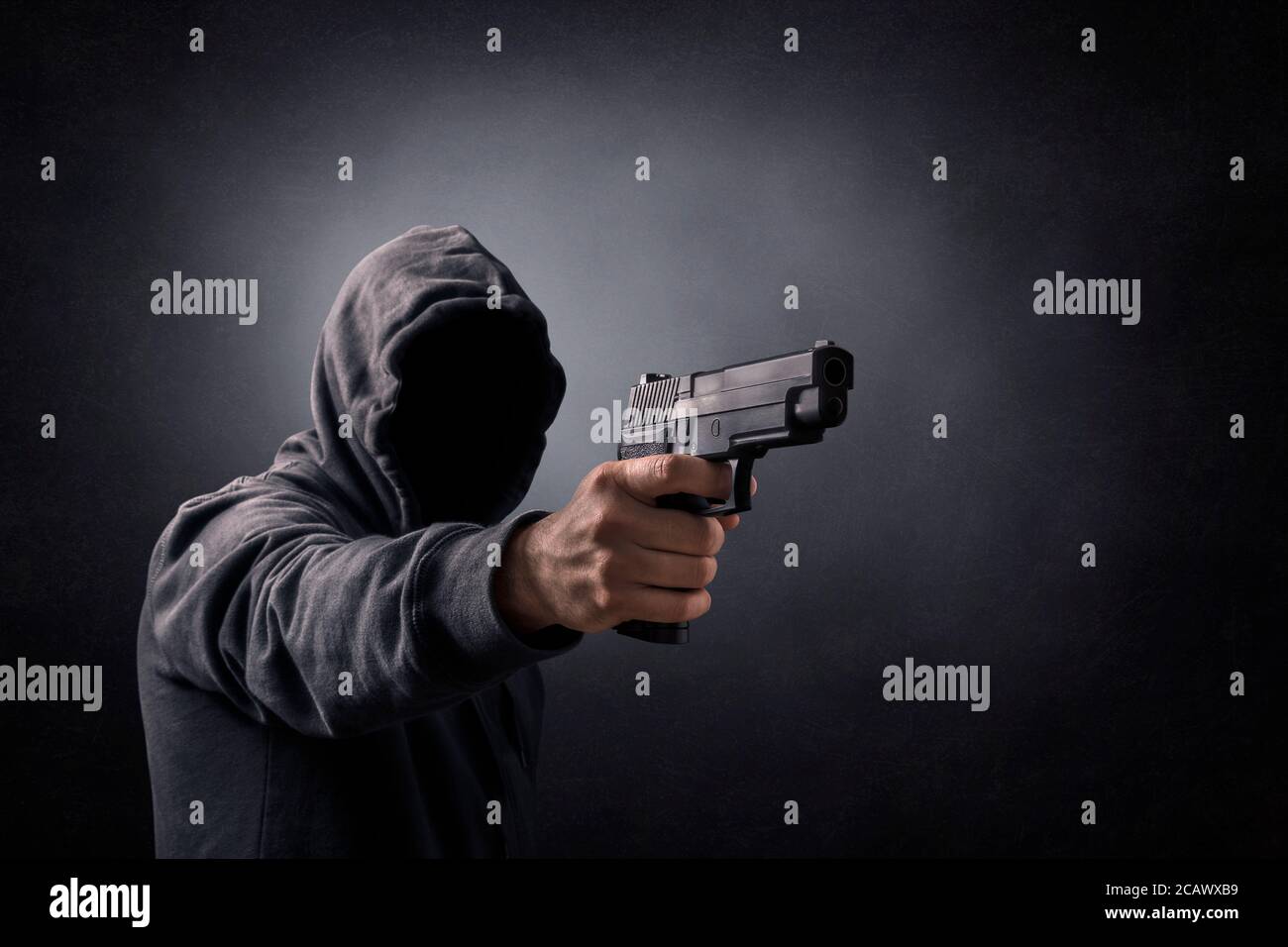 Mit Kapuze Mann mit einer Pistole in der Dunkelheit Stockfoto