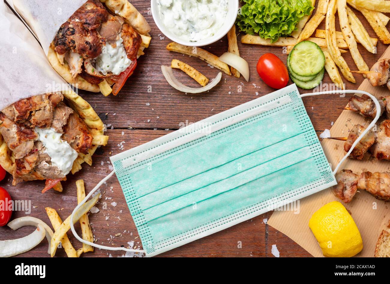 Gyro Pita, Shawarma, Coronavirus Konzept. Zwei Pita Brot Wraps mit Fleisch und Schutzmaske auf Holztisch, kopieren Raum. COVID19 Essen zum mitnehmen Stockfoto