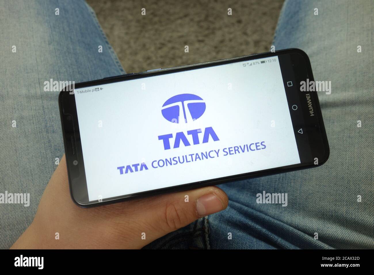 Mann mit Smartphone bei der Firma Tata Consultancy Services Limited (TCS) Logo Stockfoto