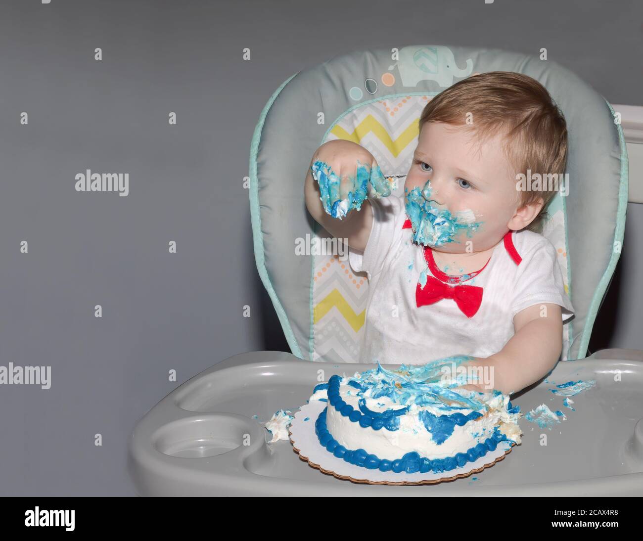 Kleinkind feiert seinen ersten Geburtstag mit zerschlackendem Kuchen. Stockfoto
