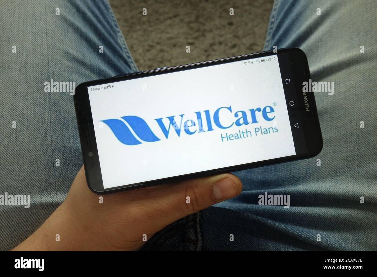 Mann hält Smartphone mit Wellcare Health Plans, Inc. Logo Stockfoto