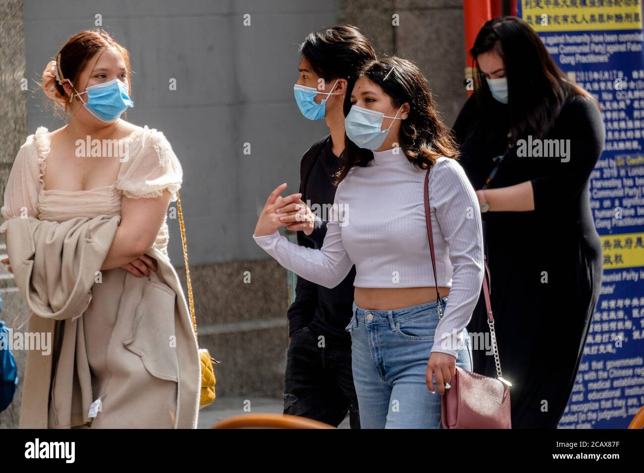 Eine Gruppe junger Leute, die Gesichtsbezüge auf der Londoner Straße tragen. Stockfoto