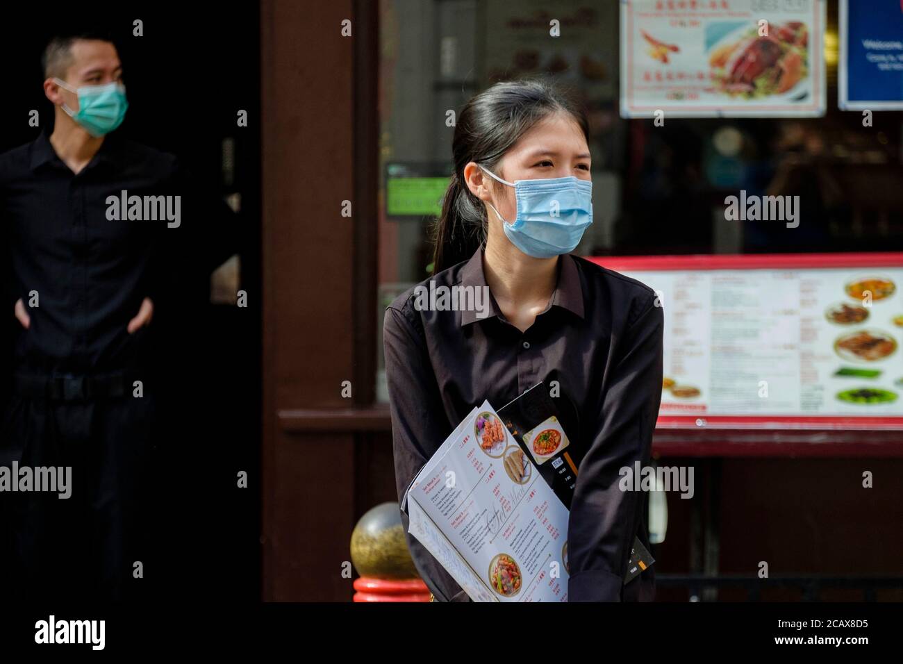 Das Personal im chinesischen Restaurant mit chirurgischen Gesichtsmasken erwartet die Gäste. Gerrard Street, Soho, London. Stockfoto