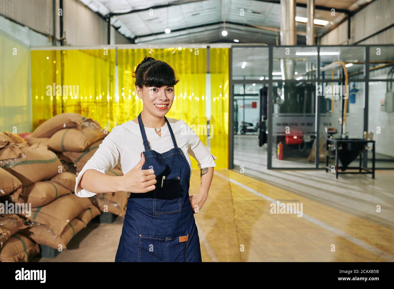 Portrait der glücklichen aufgeregt weiblichen Kaffee Rösterei Besitzer zeigt Daumen-up Und Blick auf die Kamera Stockfoto