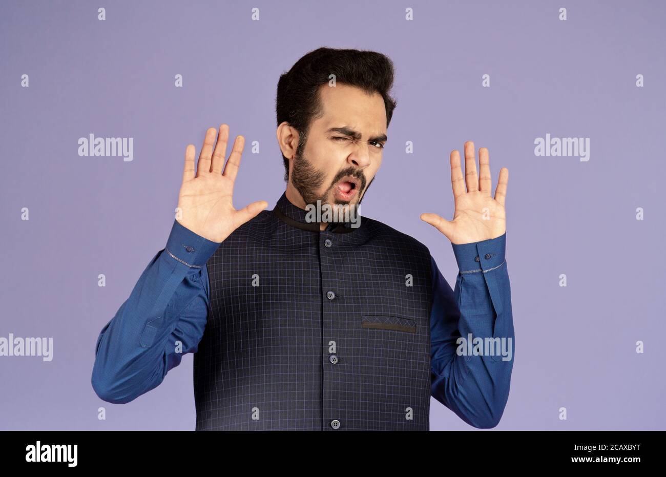 Ablehnung ausdrücken. Emotionaler indischer Mann zeigt STOP-Geste über violettem Hintergrund Stockfoto