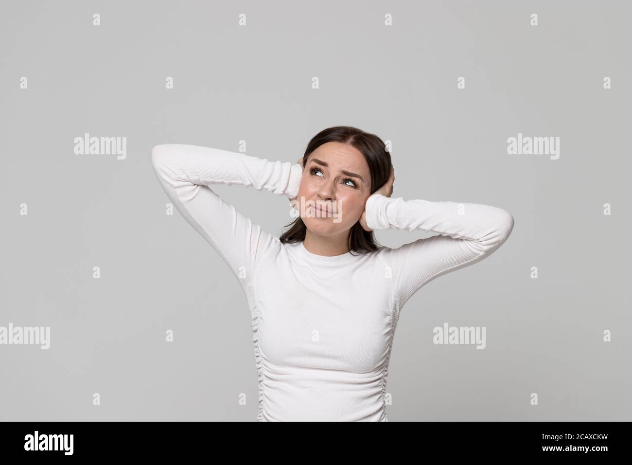 Portrait der wütend gestressten unglücklichen Frau bedeckt ihre Ohren, Blick nach oben, Kopfschmerzen Probleme mit Lärm von den Nachbarn oben, Gefühl irritat Stockfoto