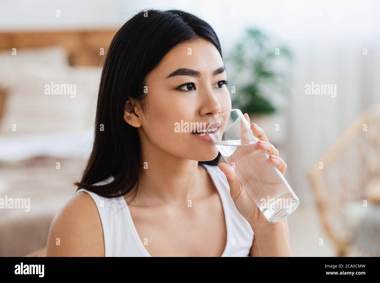 Junge asiatische Mädchen Trinkwasser im Schlafzimmer zu Hause Stockfoto