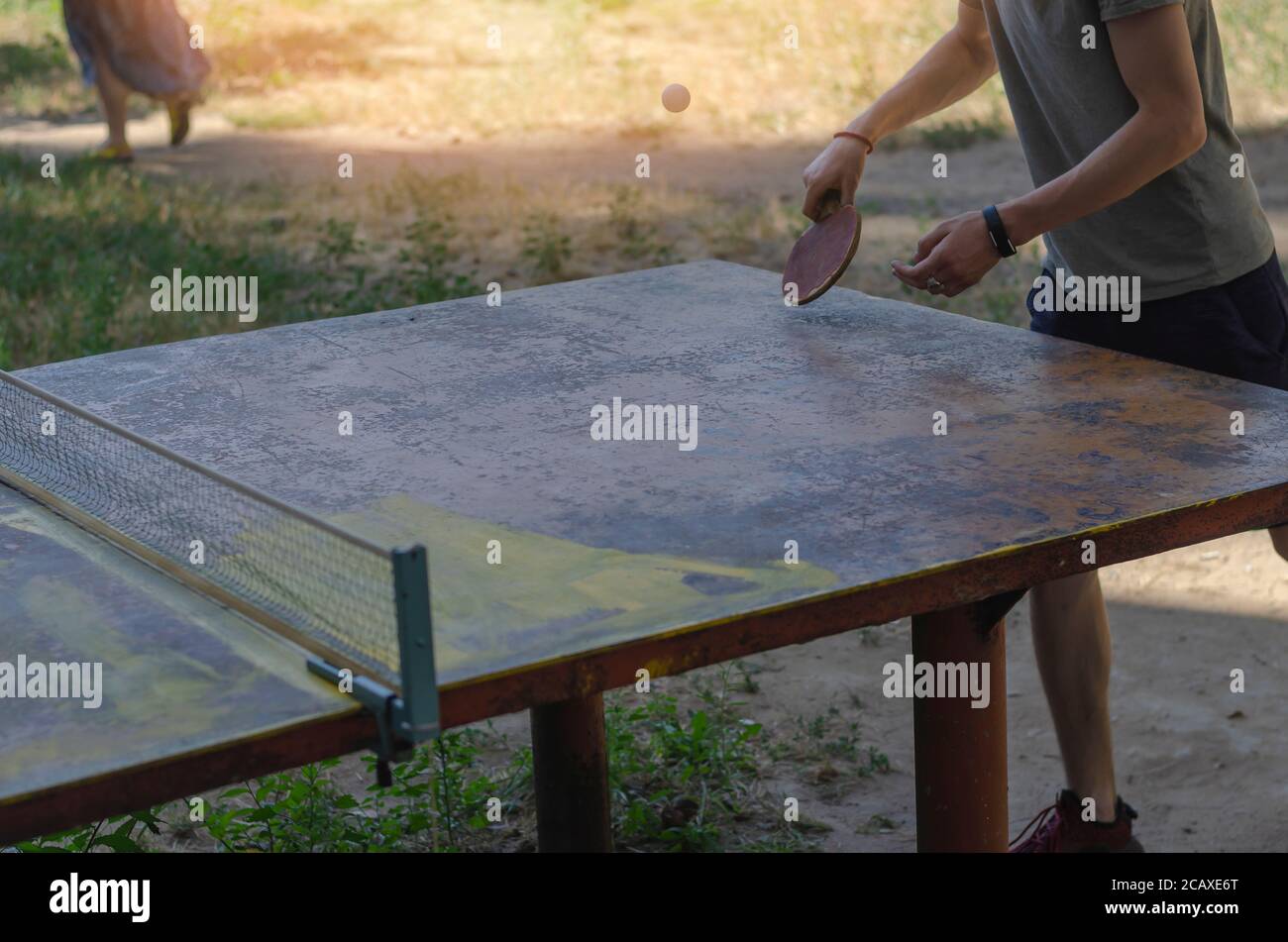 Junge kaukasische Männchen spielen Tischtennis im Freien. Metall-Tennistabelle für Outdoor-Sportarten. Aktiver Lebensstil. Warmer Sommertag. Selektiver Fokus. Stockfoto