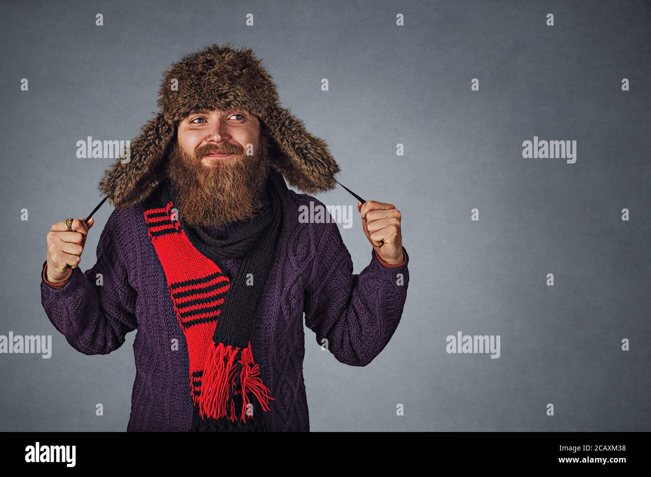 Closeup Portrait stilvolle bärtigen Mann in russischen Pelzmütze Gap und roten scraf und dunkel lila Pullover auf Seite Tagträumen nachdenklich auf g isoliert Stockfoto