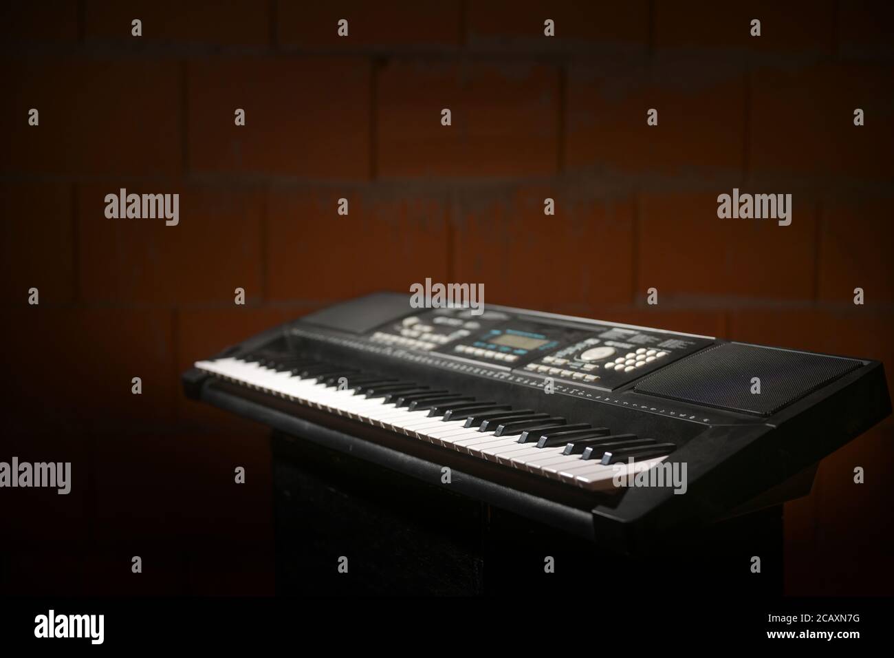 Digitales Klaviertastatur gegen eine dunkelrote Ziegelwand in der Probengarage einer Musikband, Kopierraum, ausgewählter Fokus Stockfoto