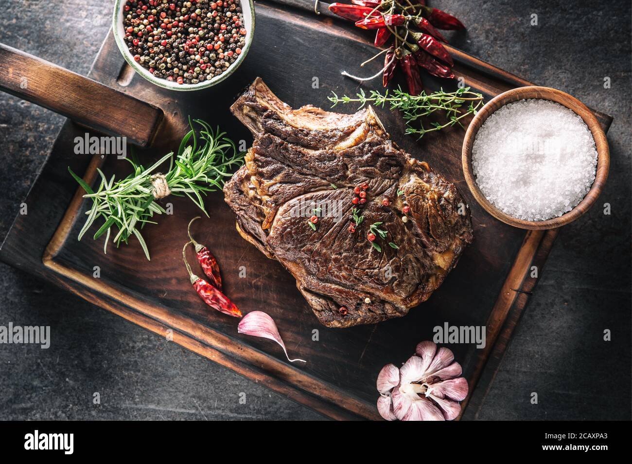 Gegrilltes Rindersteak mit Gewürzen Kräuter Salz Pfeffer und Knoblauch Auf Holzschneidebrett Stockfoto