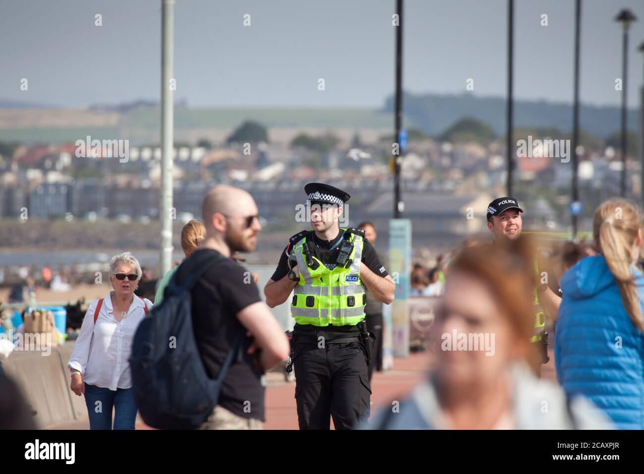 Portobello, Edinburgh, Schottland, Großbritannien. August 2020. Zwei Polizeibeamte auf Patrouille, aber ohne jede Aktivität, um sie zu kümmern. Mehr Leute am Strand und an der Promenade am späten Nachmittag. Stockfoto