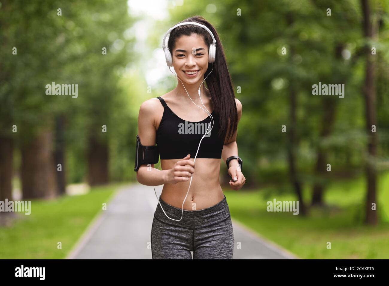 Wellness. Happy Asian Girl Jogging Im Morgen Park Hören Musik Mit Kopfhörern Stockfoto