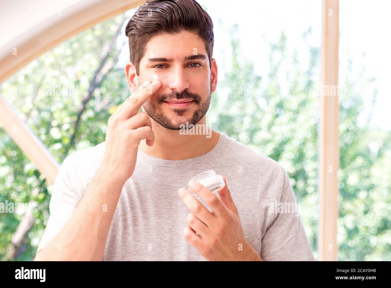 Schuss von gutaussehenden Mann Anwendung Hautpflege Gesichtsbehandlung Creme auf Gesicht im Badezimmer, während vor dem Spiegel stehen. Stockfoto