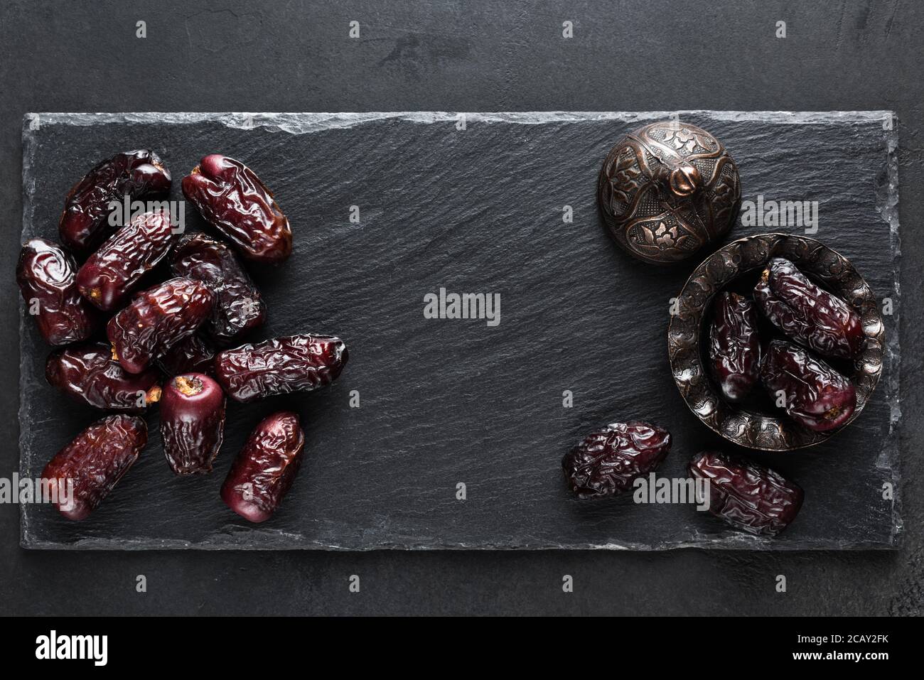 Getrocknete Datteln auf schwarzem Schiefergrund. Draufsicht mit Platz für Text. Islamisch-arabisches Essen Stockfoto