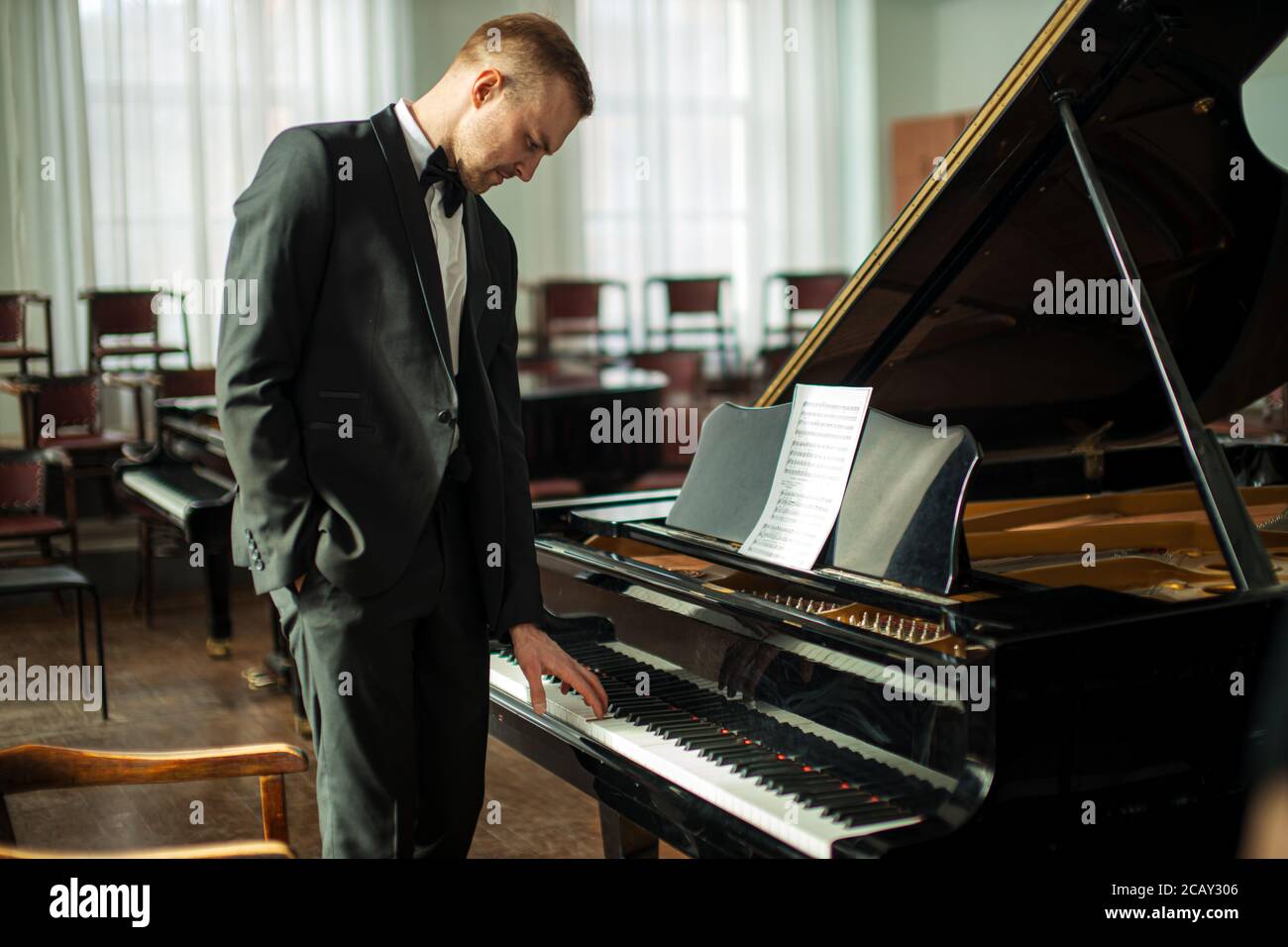 Junge kaukasische Musiker Mann in Anzug stehen neben Klavier, professionelle Pianist nach der Aufführung. Musik, Instrumente Konzept Stockfoto
