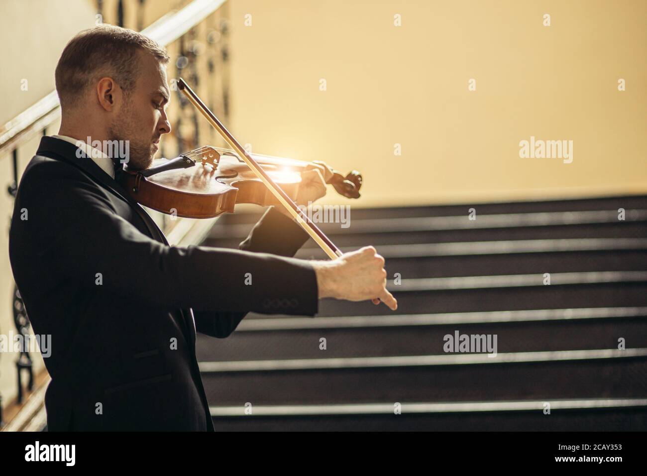 Talentierte professionelle kaukasischen männlichen Geiger spielen in der Halle, Praxis vor der Aufführung. Klassische Musik Konzept. Mann im Anzug Musik mit Stockfoto