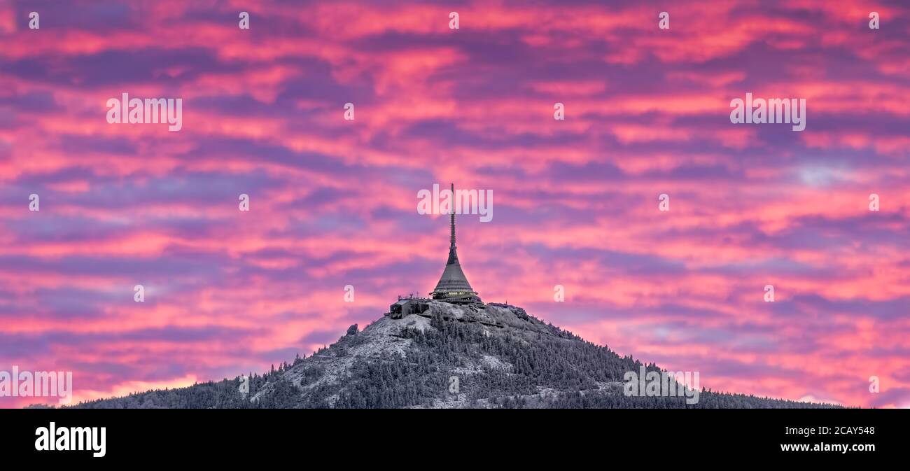 Dramatischer Liberecer Sonnenuntergang Himmel mit beleuchteten Wolken in den Bergen. Dunkelschwarze Silhouette von Bergrücken und Jested Sender Turm an der Bott Stockfoto