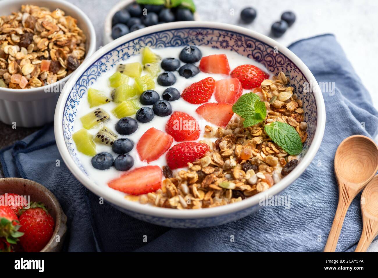 Joghurt mit Müsli, Heidelbeeren, Erdbeeren und Kiwi-Scheiben in einer Schüssel. Nahaufnahme. Gesundes Frühstück Müslischale mit viel Obst. Sauber e Stockfoto