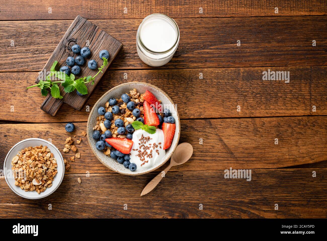 Hafergranola mit griechischem Joghurt und Sommerbeeren in einer Schüssel. Draufsicht auf einem rustikalen Holztisch Hintergrund, kopieren Raum. Ernährung, gesunde Ernährung concep Stockfoto