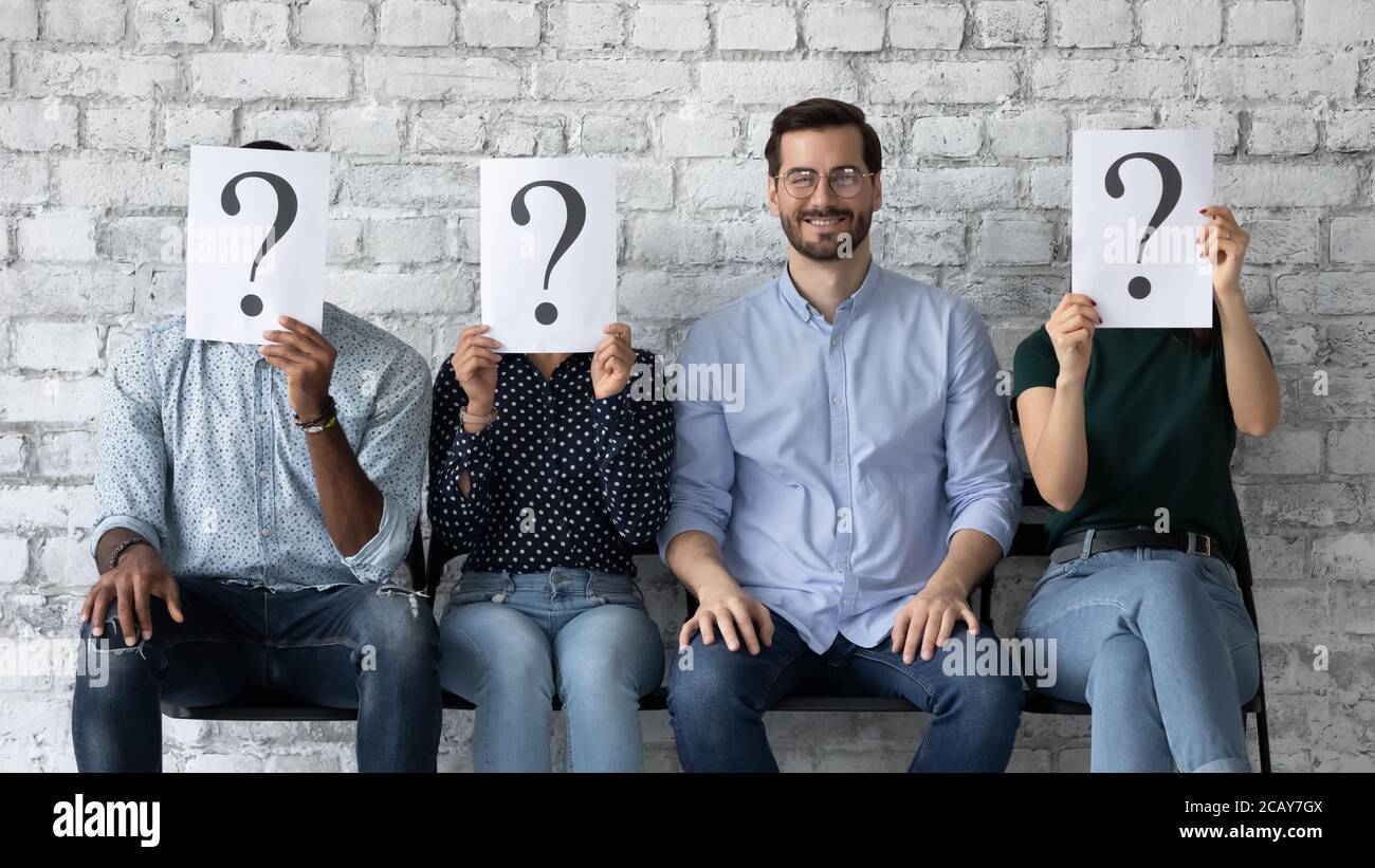Selbstbewusst lächelnder Geschäftsmann sitzt in Reihe mit unbekannten Menschen Stockfoto