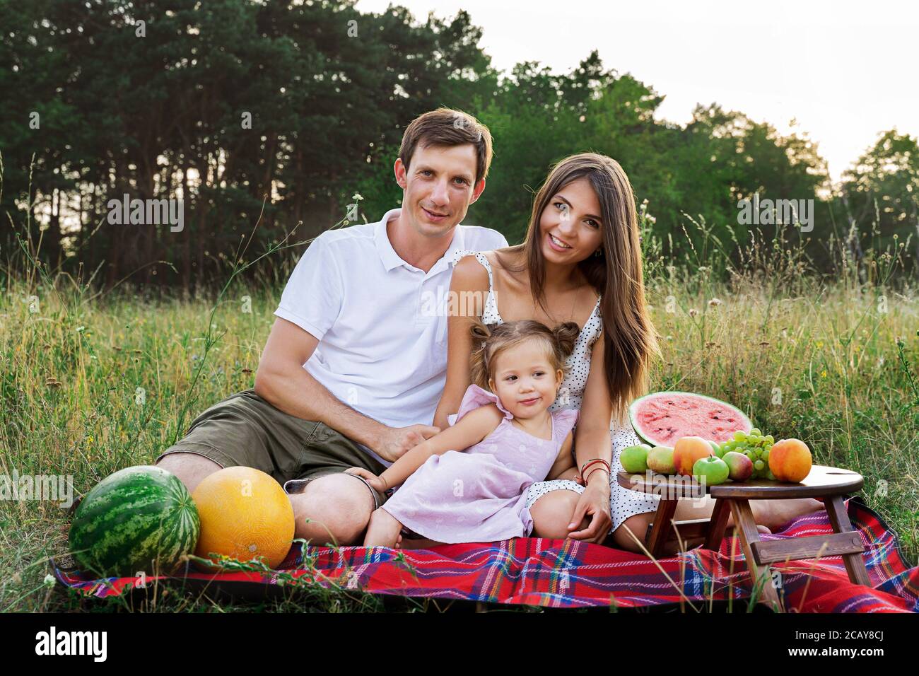 Schöne Familie, Mama, Papa und Tochter sitzen auf einem Picknick mit Wassermelone Stockfoto